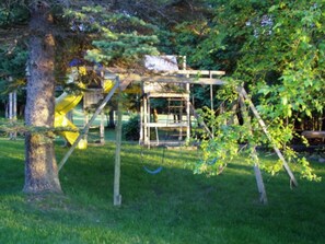 Relax in a serene garden setting with a sturdy swing for kids to play.