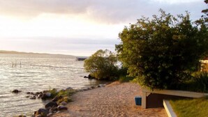 Una playa con arena, una construcción pequeña y una masa de agua.