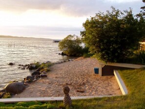 Guests can enjoy a serene lakeside setting with a sandy beach and a wooden dock extending into the water.