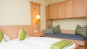 A hotel room with two beds, a wooden wardrobe, and a nightstand with a lamp. - Standard - Double room - Hotel Casa Rustica (Rust)