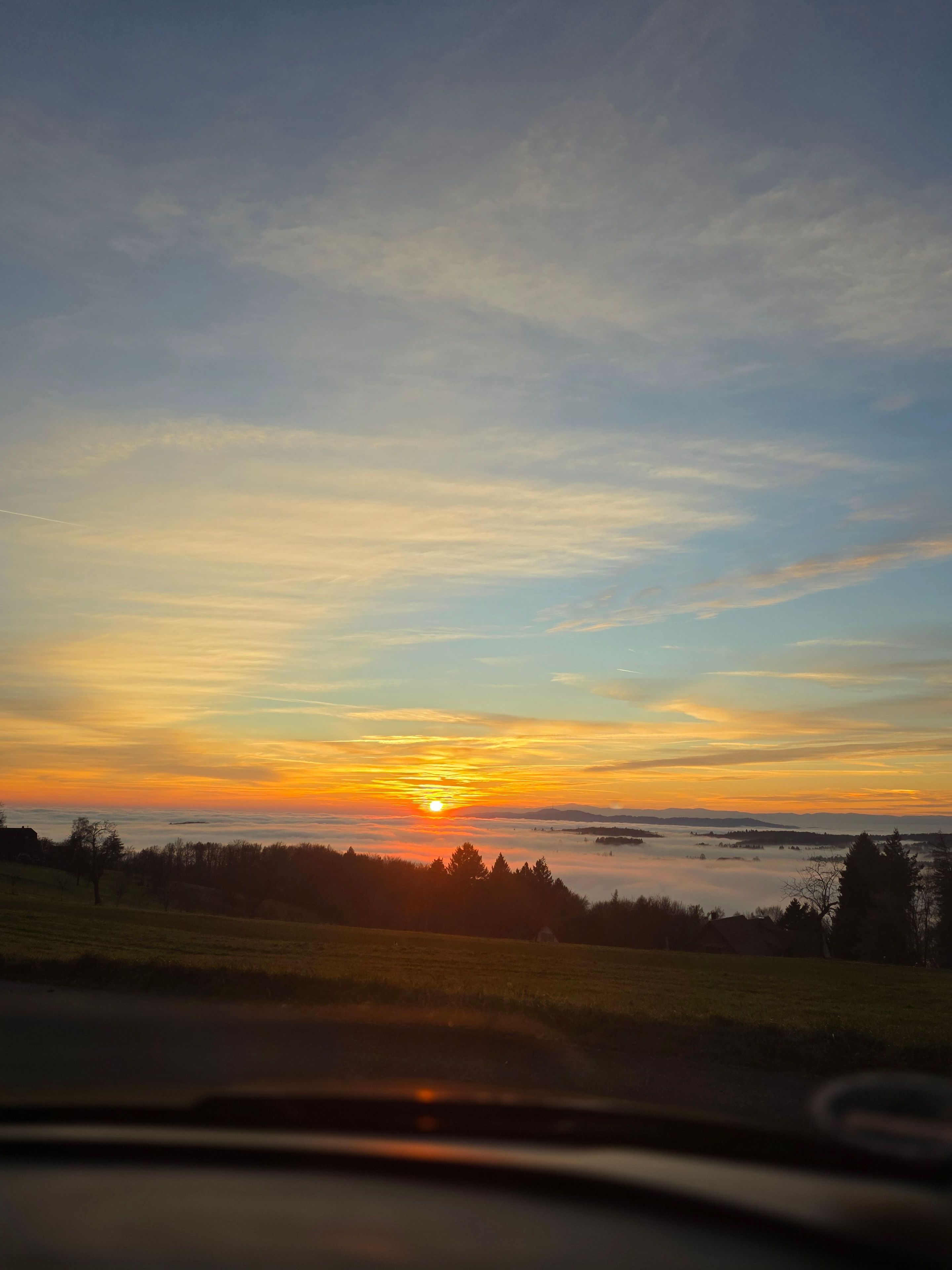 A sunset over a body of water with a distant horizon.