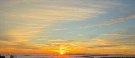 A sunset over a body of water with a distant horizon.