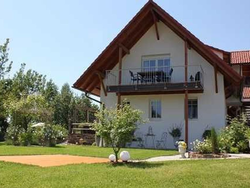 Ein zweistöckiges Haus mit Balkon, Rasen und kleinem Garten.