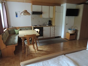 A compact kitchen with a dining area, a sofa, and a television. - Apartment 3 - Bir Karin - Apartment Karin (Schoppernau)