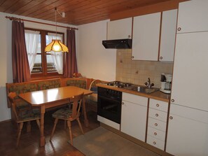 A compact kitchen with a dining table, chairs, a stove, a sink, and cabinets.