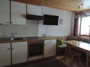 A kitchen with a stove, oven, sink, and a television mounted on the wall. - Apartment 3 - Bir Karin - Apartment Karin (Schoppernau)