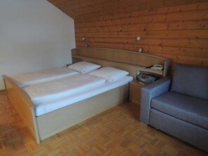 Una habitación con una cama, una mesita de noche, una lámpara y un sofá.