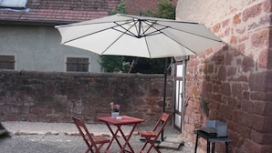 Eine Terrasse im Freien mit Tisch und Stühlen, einem großen Sonnenschirm und einem kleinen Wagen.