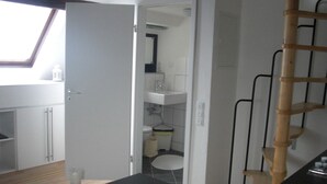Eine moderne Küche mit weißen Schränken, einer schwarzen Arbeitsplatte und einem Holzhocker.