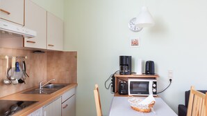 A compact kitchen with a microwave, coffee maker, and kettle on a wooden table. - Vacation apartment 3 "Chapel" - Haus Keller vacation apartments (Todtnau)