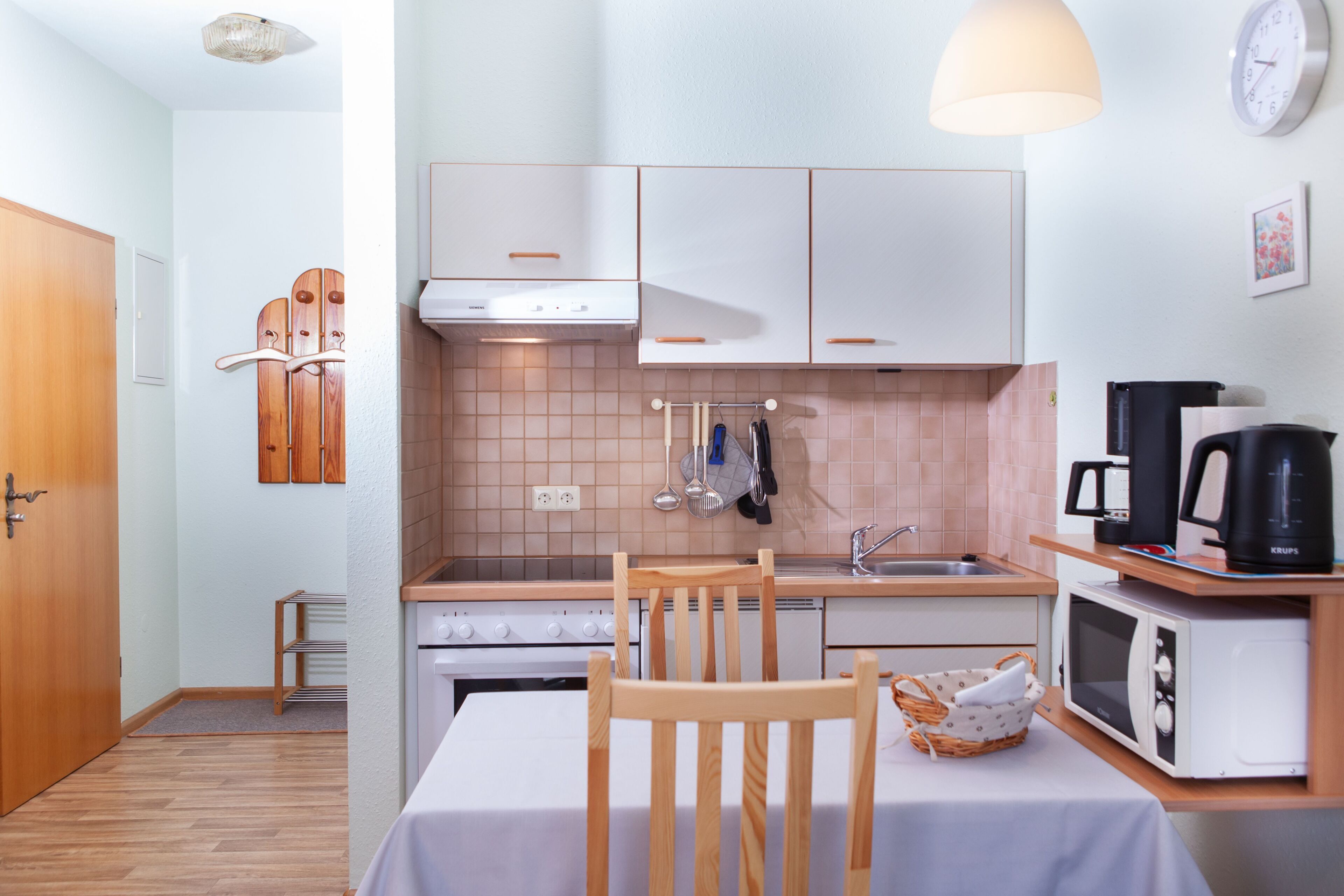 A compact kitchen with white cabinets, a stove, a microwave, and a coffee maker.
