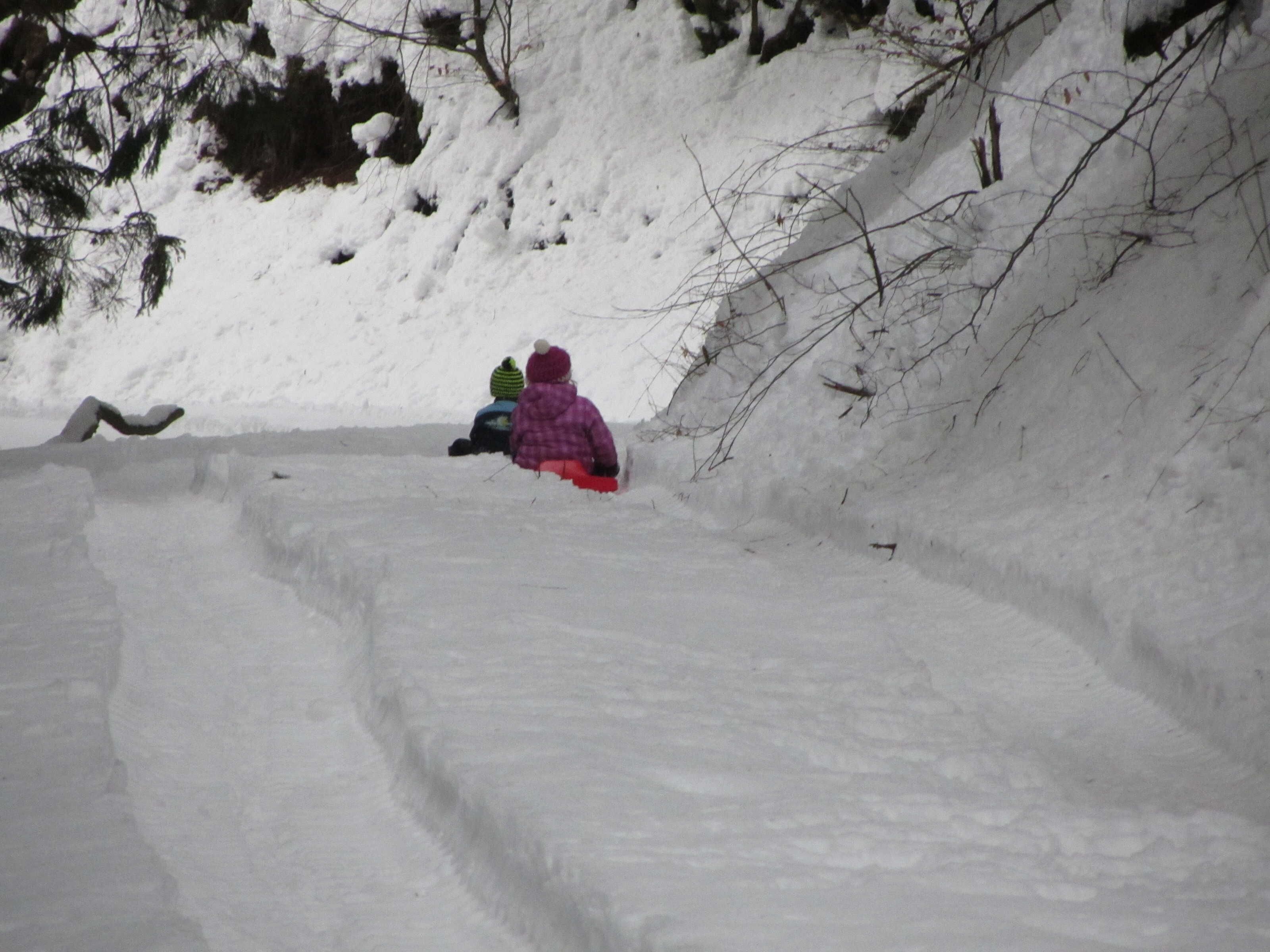 A snowy slope with a person in a purple jacket and a green hat.