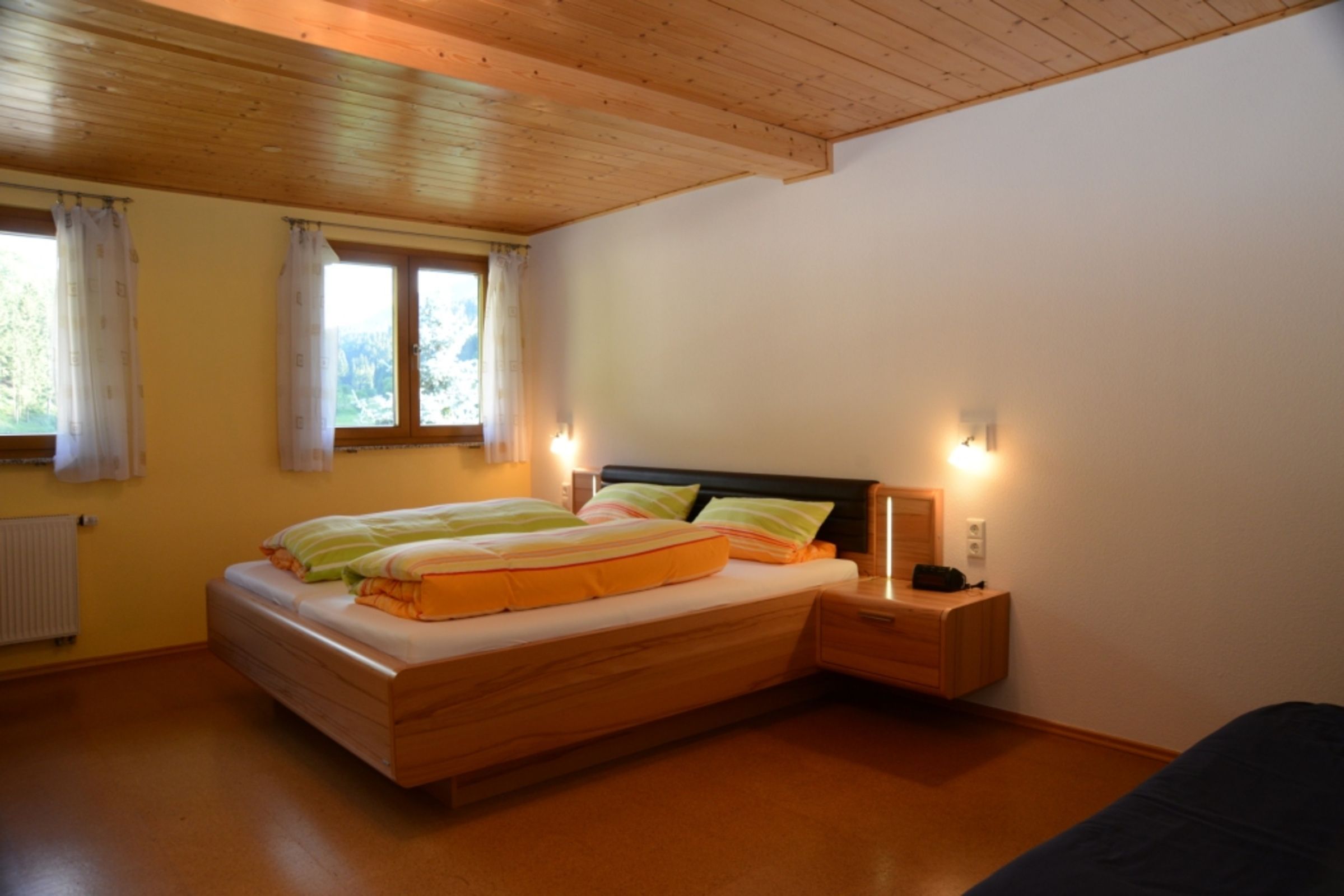 A bedroom with a wooden bed, nightstands, and a window with curtains.