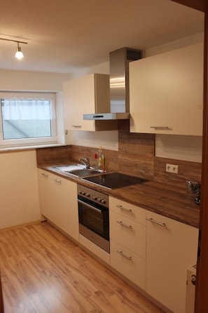 A compact kitchen with a built-in oven, a stainless steel sink, and wooden countertops. - Gästehaus Schwien - Apartment 66 qm, for max. 6 persons. (Rust)