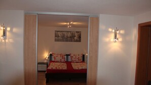 A bedroom with a bed, a nightstand, and a wall-mounted light fixture.