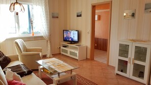 A living room with a television, a sofa, a glass coffee table, and a cabinet with glass doors. - Apartment 7 - Baltic Sea shell (Zinnowitz)