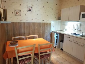 A kitchen with a wooden wall, a dining table with chairs, a microwave, and a sink. - Apartment 7 - Baltic Sea shell (Zinnowitz)