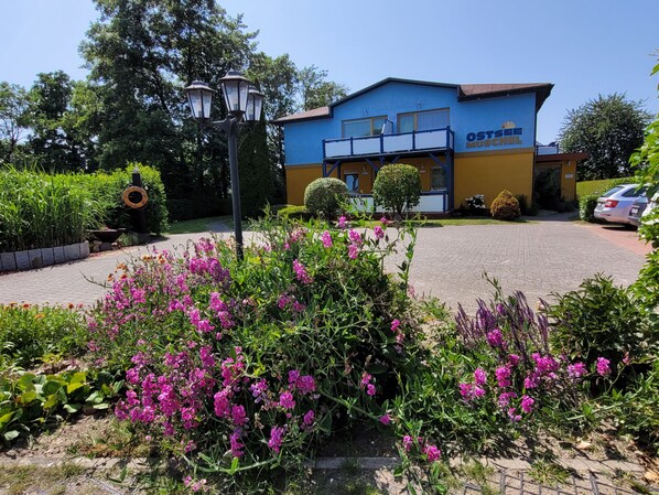 A building with a blue and yellow facade, a covered outdoor area, and a parking lot. - Apartment 7 - Baltic Sea shell (Zinnowitz)