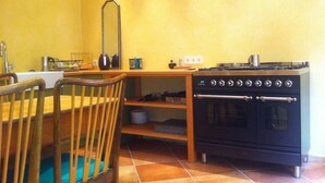 Cocina pequeña con estufa, horno y una silla de madera.