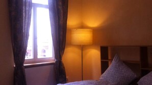 Una habitación con una cama, una ventana con cortinas y una lámpara de pie.