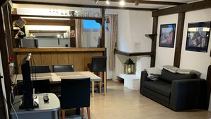 Een kamer met een bed, bureau, bank en een kitchenette.