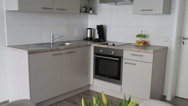 A modern kitchen with white cabinets, a built-in oven, and a sink.