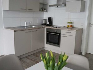 Una cocina moderna con armarios blancos, horno empotrado y un lavamanos.