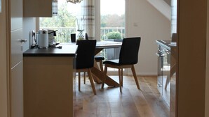 A modern kitchen with a dining area, wooden flooring, and a large window. - flammende.aussicht, Germany (Freiamt)