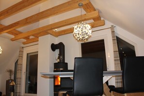 A dining area with a wooden ceiling, a black table, and black chairs.