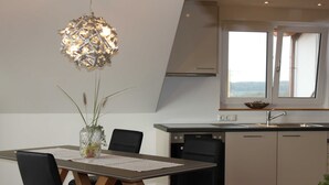 A modern kitchen with a dining table, chairs, a vase with plants, and a unique chandelier. - flammende.aussicht, Germany (Freiamt)
