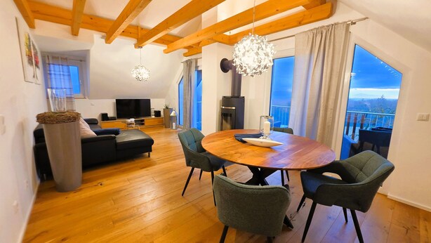 A spacious living area with a wooden floor, a round dining table with chairs, a sofa, a television, and a fireplace. - flammende.aussicht, Germany (Freiamt)