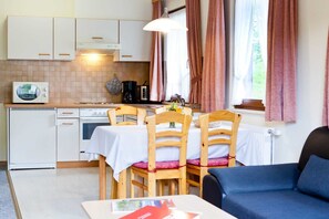 A compact kitchen with white cabinets, a microwave, and a dining area with a table and chairs.