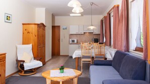 Un espacio habitable compacto con sofá, mesa de comedor y kitchenette.