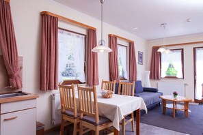 Ein Zimmer mit Esstisch, Stühlen, einer Couch und einem kleinen Tisch mit Lampe.