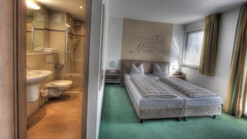 Une chambre d’hôtel avec une douche, des toilettes et un lit recouvert d’une moquette verte.