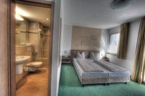 A hotel room with a shower, toilet, and a bed with a green carpet. - Double room comfort - Hotel-Restaurant Schwörer (Lenzkirch)