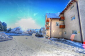 Un edificio con el suelo cubierto de nieve, un coche aparcado y un cielo despejado.