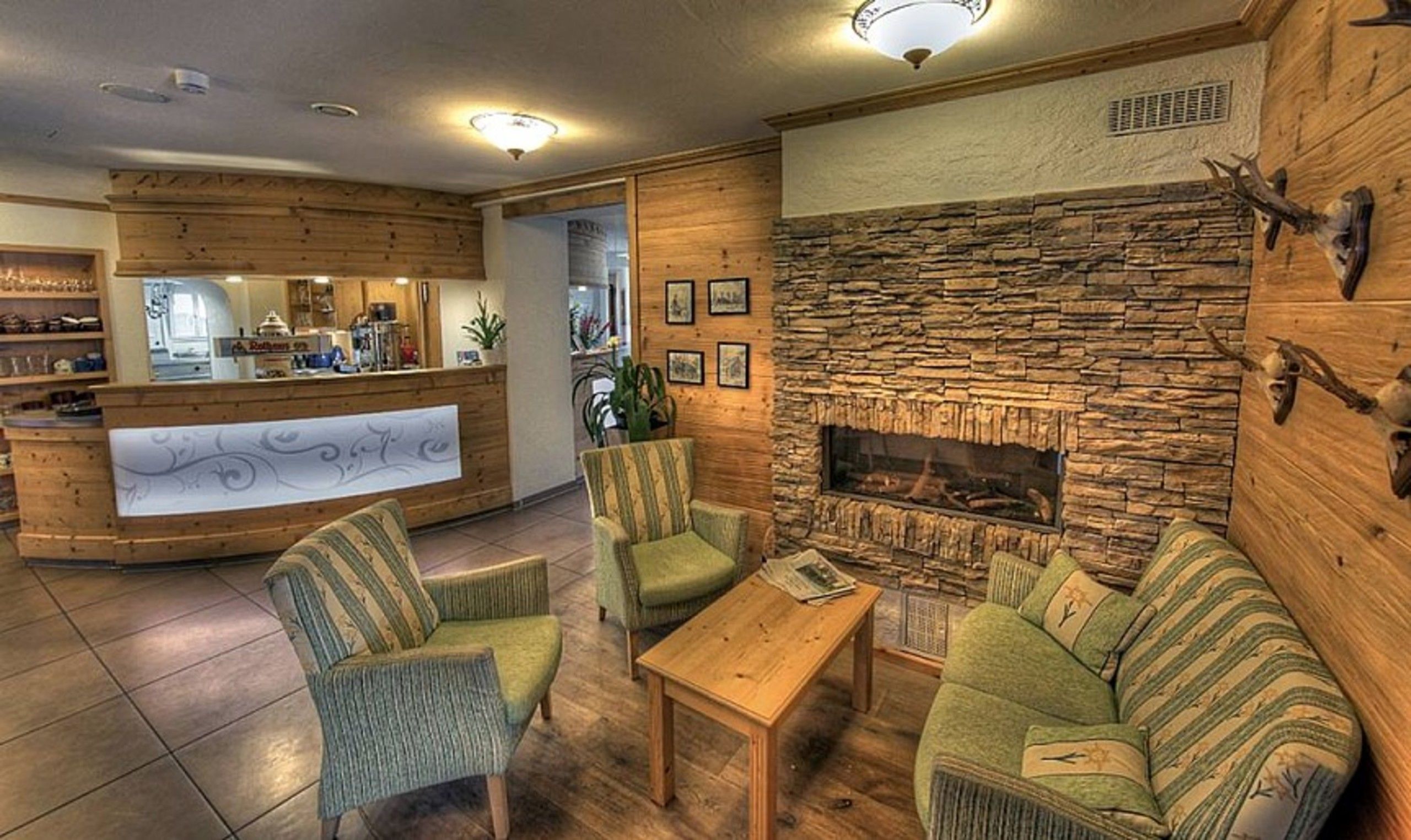 A cozy lobby with a stone fireplace, wooden reception desk, and comfortable seating.