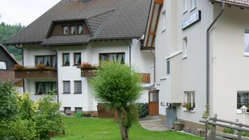 Un bâtiment à deux étages doté d’un balcon, d’un petit jardin et d’une clôture en bois.