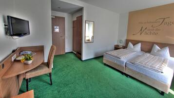 Une chambre d’hôtel équipée d’un bureau, de deux lits, d’un miroir et d’un mur orné d’une citation inspirante.