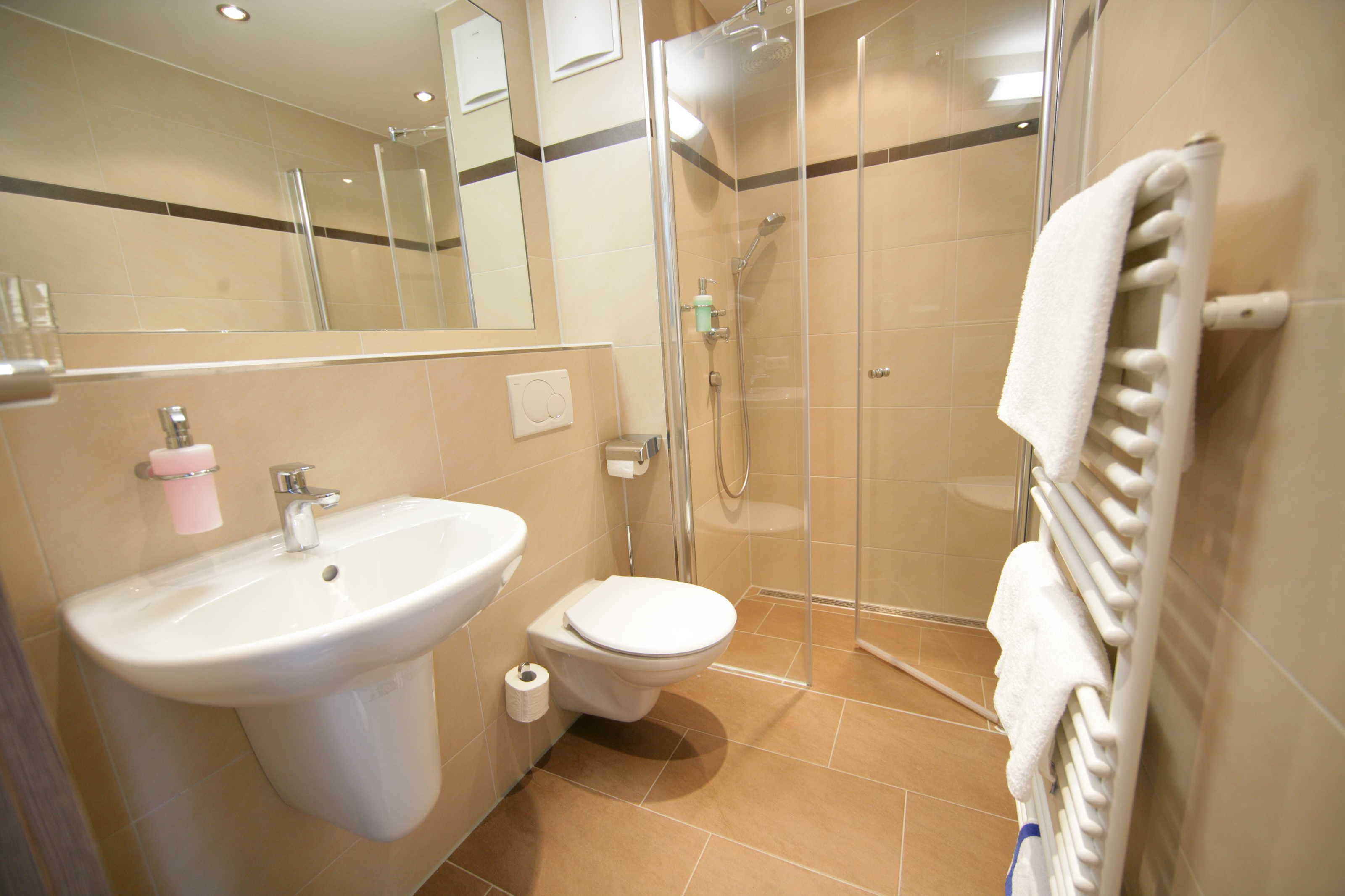A bathroom with a sink, toilet, shower, and a towel rack.