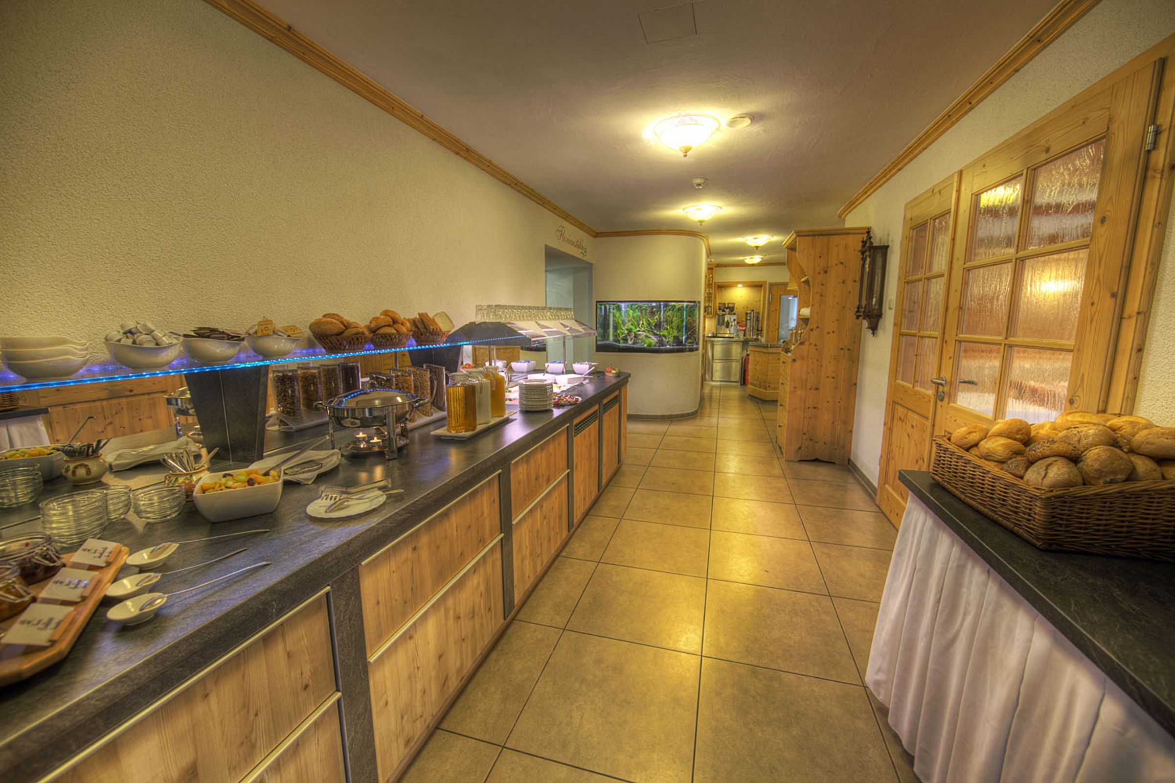 Un buffet proposant divers plats, un coin café et un aquarium dans une chambre d’hôtel.