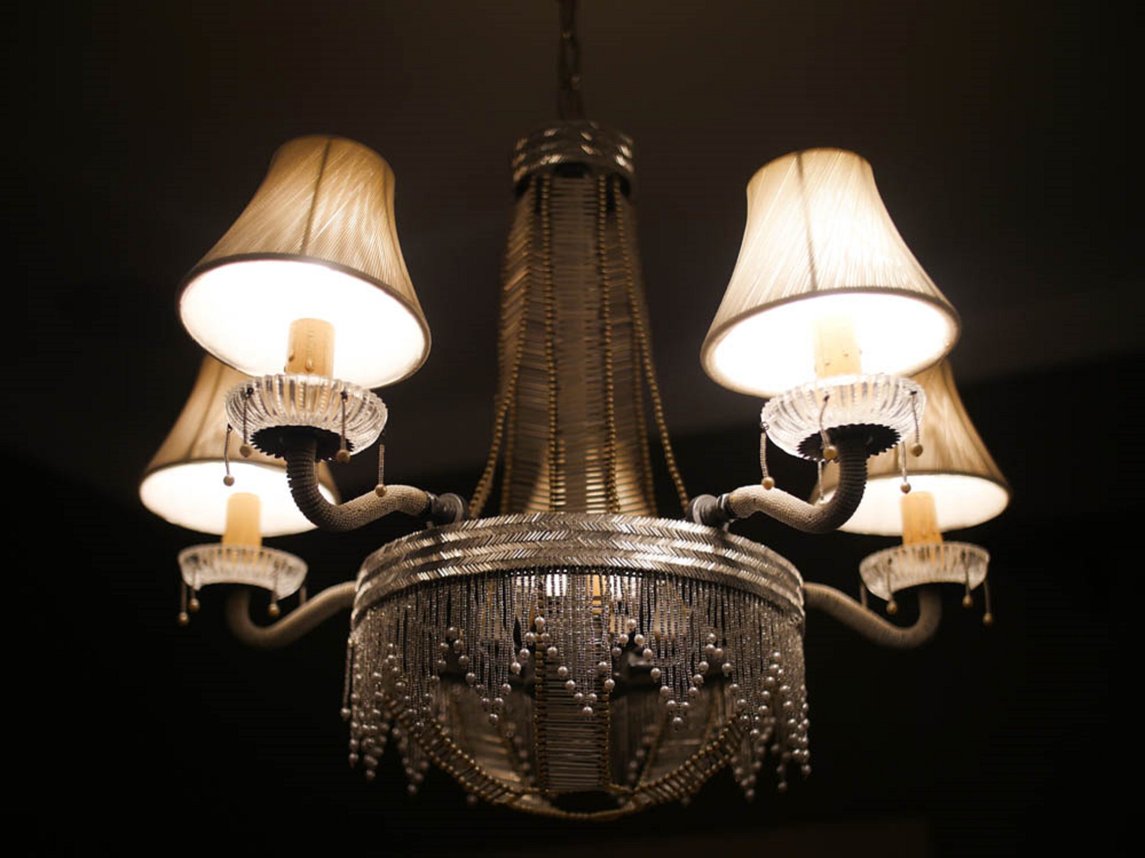 A chandelier with three lampshades and a central decorative element.