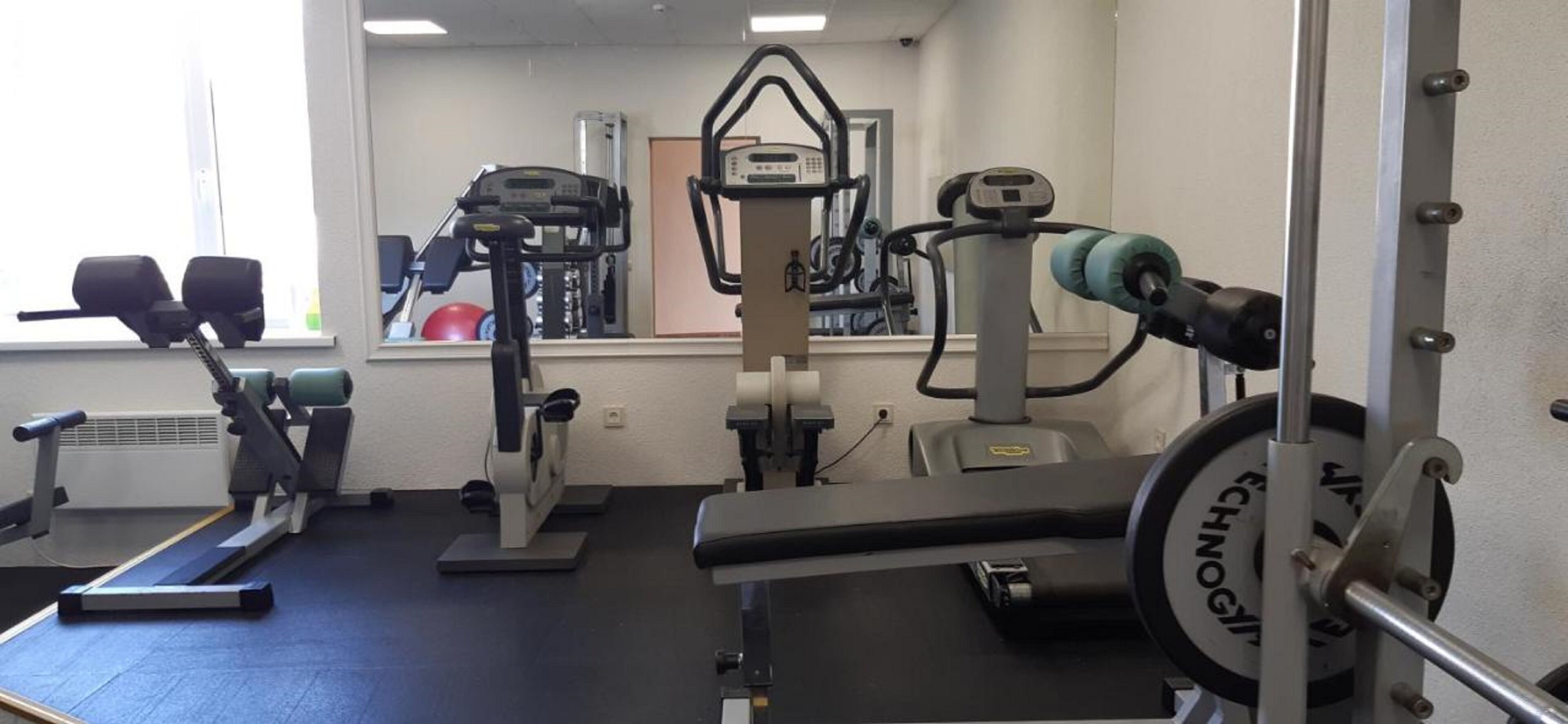 A gym with various exercise equipment including treadmills, a stationary bike, and weight machines.