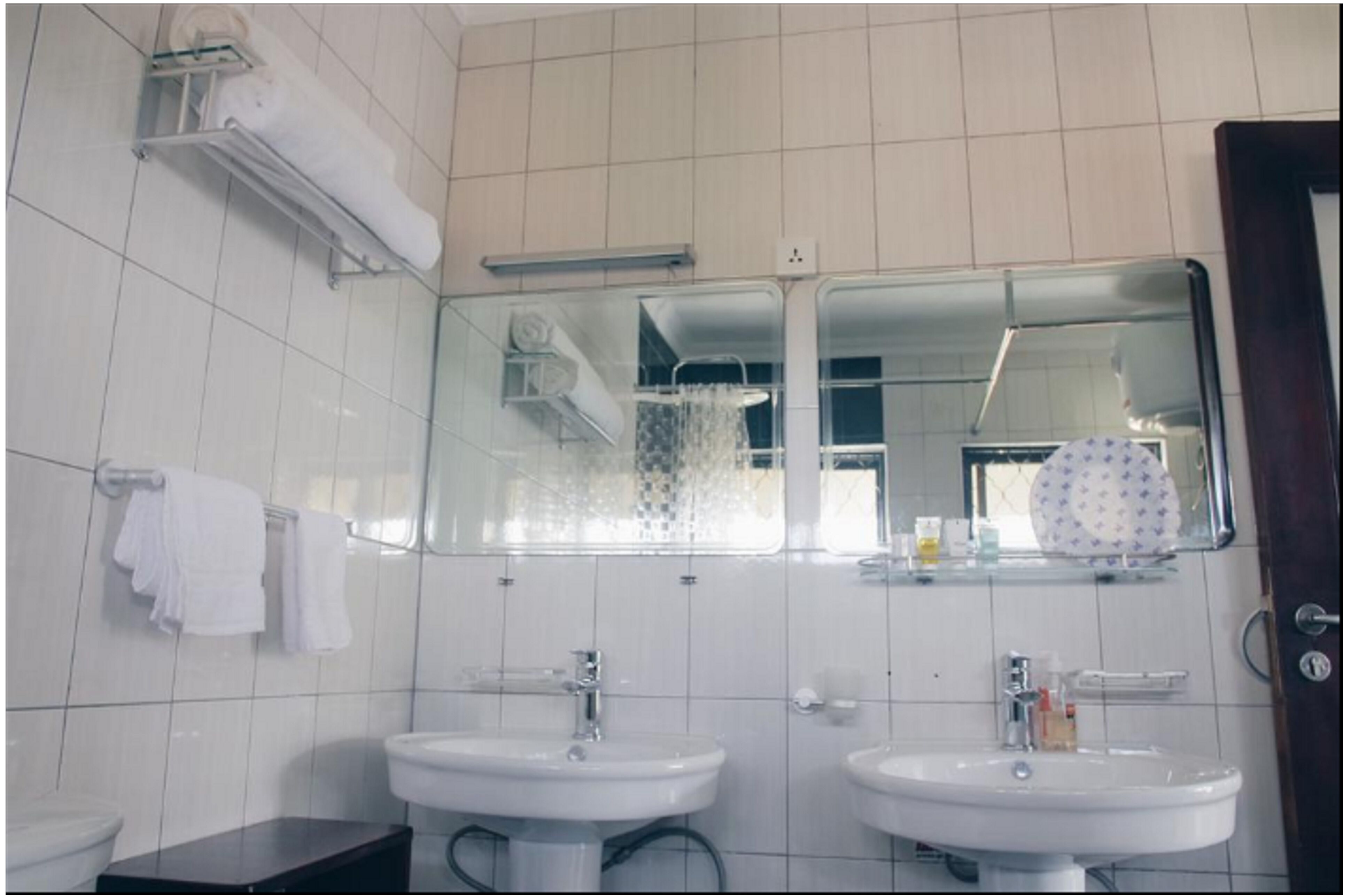 Een badkamer met twee wasbakken, een spiegel en een handdoekhouder.