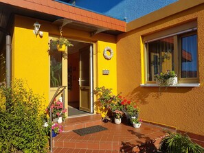 A yellow building with a door, potted plants, and a window. - Apartment 15 - Baltic Sea shell (Zinnowitz)