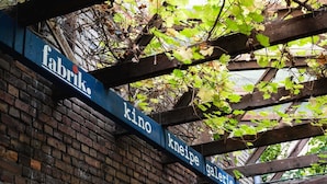 Une enseigne avec les mots « fabrik », « kino », « kneipe » et « galerie », fixée à une structure en bois.