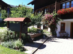 A rustic building with a garden area, a wooden bench, and a mailbox.