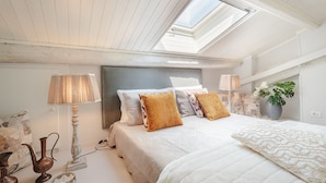 A bedroom with a sloped ceiling, a skylight, a bed with patterned pillows, bedside lamps, and decorative items. - Spacious Home with Elevator along Via Guinigi inside the Lucca Walls (Lucca)