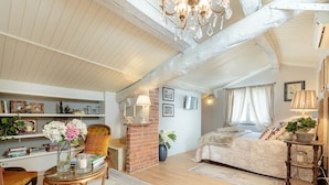 A cozy bedroom with a large bed, a wooden chair, a glass table, and a brick fireplace. - Spacious Home with Elevator along Via Guinigi inside the Lucca Walls (Lucca)